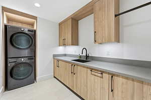 Laundry room with estacked washer and dryer, light tile patterned flooring, and recessed lighting