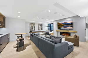 Living area with recessed lighting, a glass covered fireplace, and light wood finished floors