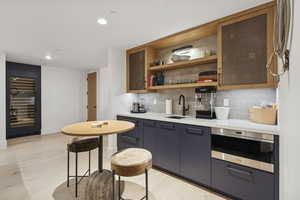 Bar featuring open shelves, tasteful backsplash, recessed lighting, glass insert cabinets, and light wood-style flooring