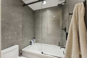 Full bathroom with bath / shower combo with glass door and tile walls