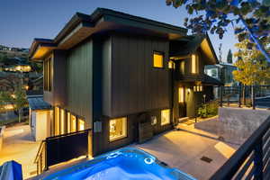 Back of house with an outdoor hot tub and board and batten siding