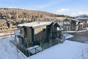 Snow covered back of property with a residential view and a mountain view