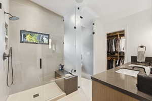 Full bath with a shower stall, vanity, a walk in closet, and light tile patterned flooring