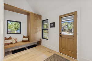 Mudroom featuring light wood-style flooring and vaulted ceiling