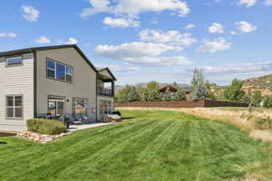 Back of property featuring a balcony, a patio area, and a mountain view