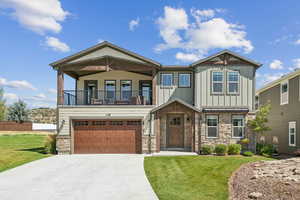 Craftsman house with stone siding, a front yard, and driveway