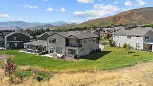 Rear view of house featuring a residential view, a balcony, a patio, a mountain view, and a lawn
