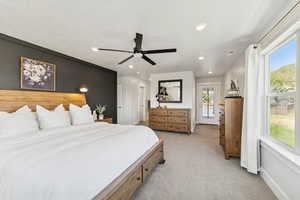 Bedroom with light colored carpet, a ceiling fan, recessed lighting, access to exterior, and a textured ceiling