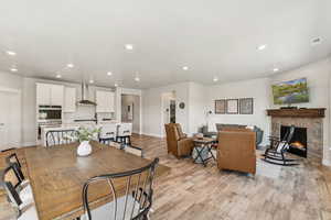 Dining space with light wood finished floors, recessed lighting, and a stone fireplace