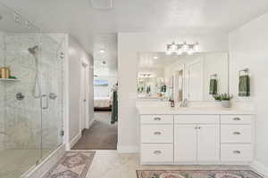 Bathroom with vanity, a marble finish shower, ensuite bathroom, a textured ceiling, and light marble finish floors
