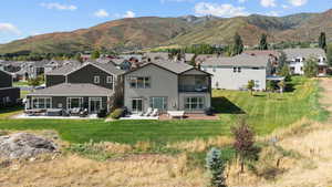 Rear view of house with a patio, a residential view, a mountain view, and a lawn