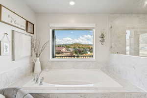 Bathroom with a garden tub, healthy amount of natural light, recessed lighting, and a marble finish shower