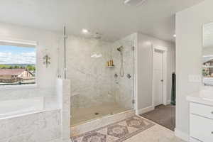 Full bath featuring vanity, a stall shower, a garden tub, and a textured ceiling