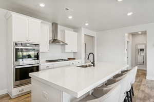 Kitchen featuring white cabinets, appliances with stainless steel finishes, light wood-style floors, a kitchen breakfast bar, and a textured ceiling