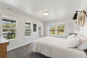 Bedroom with a textured ceiling, dark carpet, and a mountain view