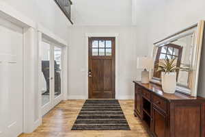 Foyer entrance with light wood-type flooring, french doors, and a towering ceiling