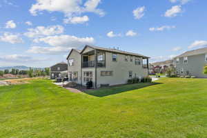 Rear view of property with a balcony, a mountain view, a yard, and a patio area