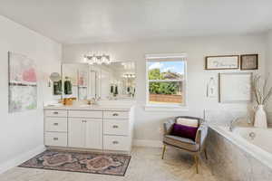 Bathroom featuring vanity, a garden tub, a textured ceiling, and light marble finish flooring