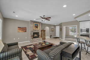 Living room featuring a fireplace, light tile patterned flooring, ceiling fan, arched walkways, and recessed lighting