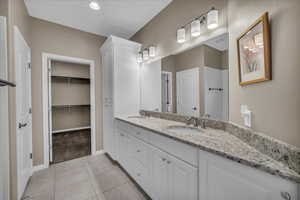 Bathroom featuring double vanity, light tile patterned flooring, a spacious closet, light carpet, and recessed lighting