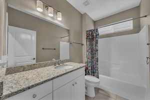 Bathroom featuring vanity, light tile patterned floors, and shower / bath combo with shower curtain