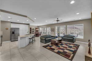 Living area featuring a ceiling fan, recessed lighting, a textured ceiling, and light tile patterned flooring
