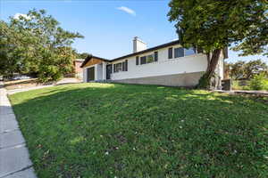 View of front of home featuring a garage, a front lawn, a chimney, and brick siding