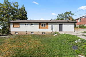 Back of property with brick siding and a yard