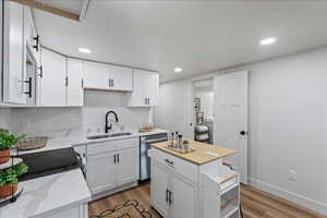 Kitchen featuring wood counters, white cabinetry, light wood finished floors, dishwasher, and recessed lighting