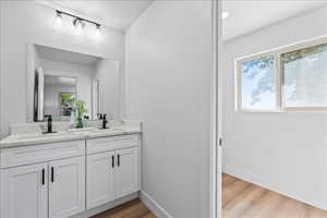 Full bath with light wood-style floors and double vanity