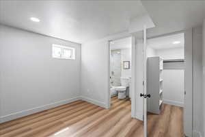 Unfurnished bedroom featuring light wood-style floors, a spacious closet, recessed lighting, and connected bathroom