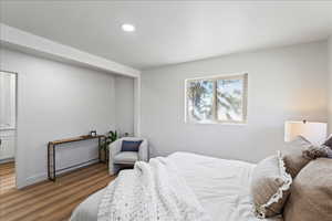 Bedroom with wood finished floors, recessed lighting, and baseboard heating