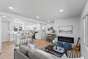 Living area with a glass covered fireplace, recessed lighting, and light wood finished floors