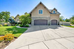 View of front of house with stone siding, stucco siding, a garage, and concrete driveway