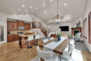 Dining room with stairs, a fireplace, a chandelier, recessed lighting, and light wood-style flooring