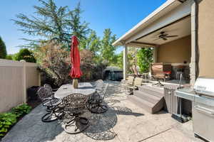 Fenced backyard with outdoor dining area, grilling area, a patio, and ceiling fan