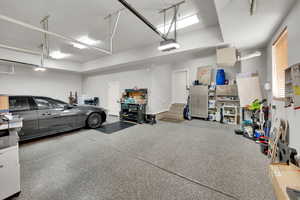 Garage featuring a garage door opener and baseboards