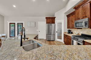 Kitchen featuring recessed lighting, light stone counters, stainless steel appliances, light wood-type flooring, and tasteful backsplash