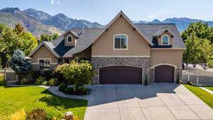 View of front of home with stone siding, a mountain view, stucco siding, and a garage
