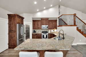 Kitchen with a breakfast bar area, a peninsula, stainless steel appliances, tasteful backsplash, and light stone countertops