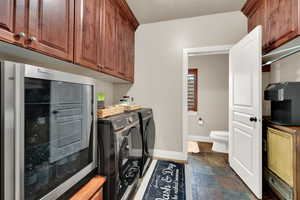 Washroom with separate washer and dryer, dark stone finish flooring, and beverage cooler