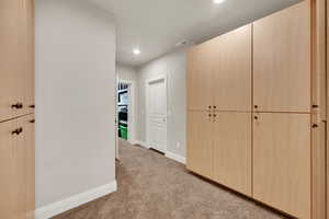 Corridor with light carpet and recessed lighting