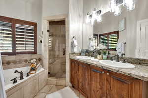 Full bathroom with a shower stall, a garden tub, double vanity, and light tile patterned floors