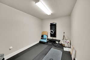 Workout area with baseboards and a textured ceiling