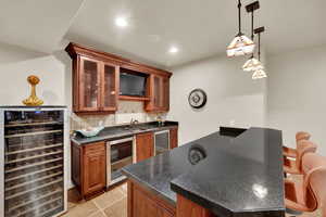 Kitchen featuring tasteful backsplash, wine cooler, glass insert cabinets, brown cabinets, and recessed lighting
