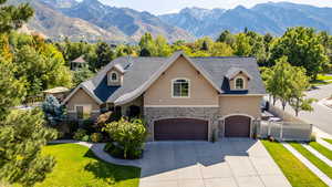 View of front of property with stone siding, stucco siding, a mountain view, a garage, and concrete driveway