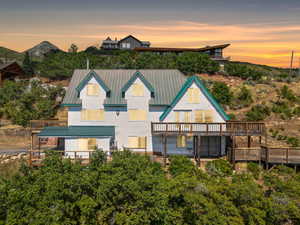 Back of house at dusk with a deck and a metal roof