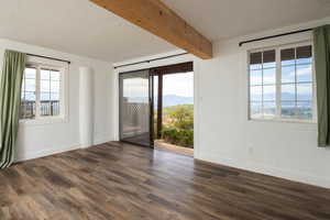 Unfurnished room with a mountain view, beam ceiling, dark wood finished floors, and a textured ceiling