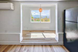 Unfurnished dining area with light wood-style floors, a mountain view, and a wall mounted air conditioner