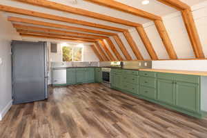 Kitchen featuring lofted ceiling, stainless steel appliances, dark wood-type flooring, and green cabinets
